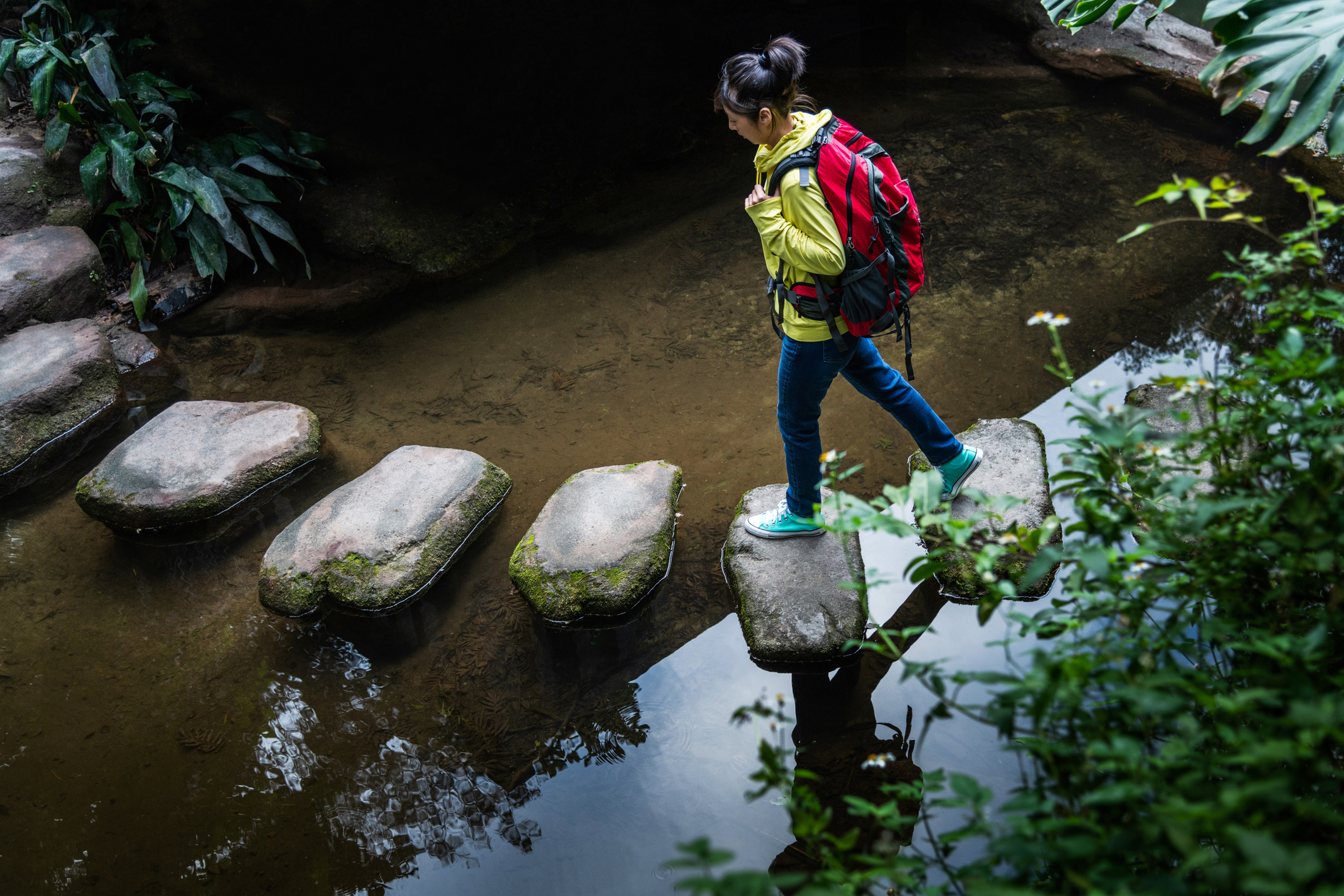 Female backpacker walking on stepping stones